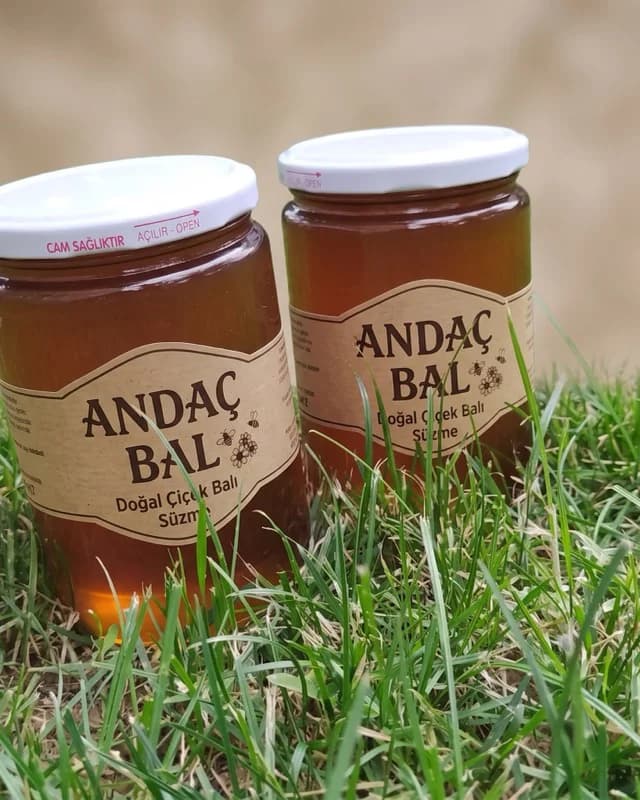 Çimenlerin üstünde iki Andaç Bal süzme çiçek balı kavanozu